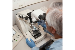 Researcher looking through microscope in lab.