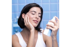 Image Woman in bathroom holds spray to face