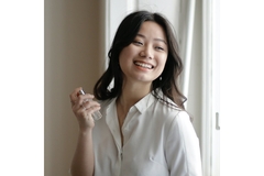 Image A woman smiling and spraying perfume on her neck.