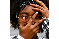 A woman adjust her glasses on her face using her whole hand.