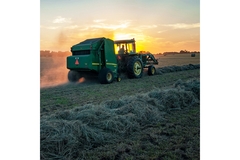Image Farmer on tractor in field at sunset.