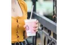 woman holding a pink cup with a plastic straw in her hand