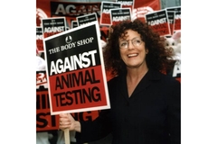 Image Body shop founder holding a sign thats says "against animal testing"