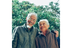 Image An older couple hugging in front of a tree.