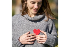 Image Women holds heart cut out on her chest