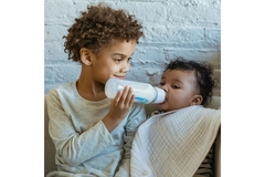 Young boy feeding a toddler with formula