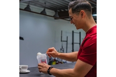 Image Man scooping protein powder in his drink.