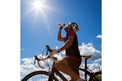Athlete on a sports bicycle, drinking water from a bottle.