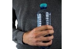 Man holding water bottle against his chest.