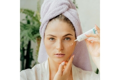 Image A woman with dots of eyecream on her face.