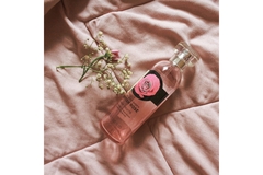 Image The Body Shop body spray laying on a pink bed sheet.