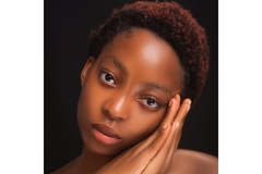 Image woman with short hair poses with hands on one side of the cheek.