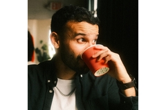 Image man sipping from a red coffee cup looking out of the window