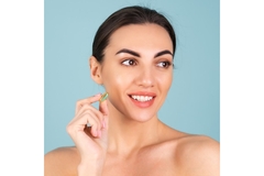A woman smiling and holding a supplement.