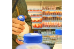 Image Person looking at plastic-based milk bottles in supermarket.