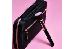 Image A makeup brush resting on a makeup bag.