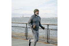 Older man runs by a river.