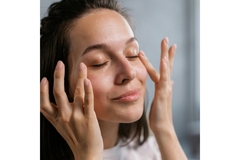 smiling woman applies cream to her face.