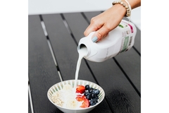 Image Woman pouring milk on cereal and fruit