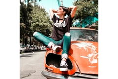 Image A girl sits on an older Nissan 280 ZX and soaks up the sun in the city.