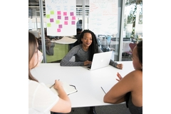 Image Three women sitting at a desk and talking.
