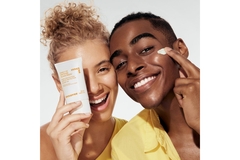Image Two people holding up a moisturizer and putting it on their face.
