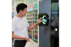 Image Man placing empty bottle in return vending machine.