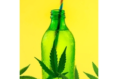 Image A green bottle with a clear liquid, a striped straw and a marijuana leaf in it.