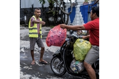 Image A group of men holding trash bags filled with plastic.