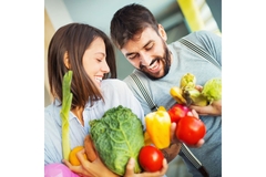 Man and woman holding various vegetables.