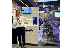 Image A woman standing next to a separator at a trade show.