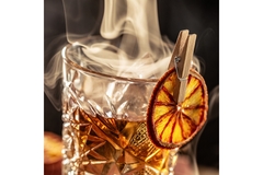 Image Smoke coming out of a light orange colored drink in a glass.