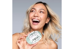 Image A woman holding the Opal at home teeth whitening while smiling.