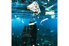 scuba diver's fins underwater along with plastic pollution debris floating