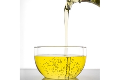 Image Yellow oil pouring from beaker to a glass.