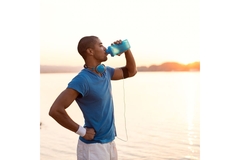 Image Man in sports outfit drinking from a blue bottle.