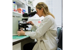 Researcher looking into microscope.