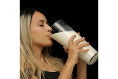 A woman in a black dress drinking milk from a big glass.