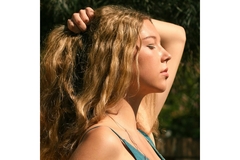 A woman holding her hair and facing the sun with it on her face.