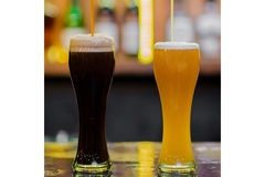 Two different kinds of beer is placed on a table.