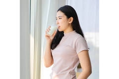 Image Woman drinking soy milk from a glass.
