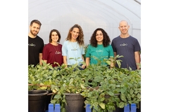 Image Three women and two men standing next to each other in colorful t shirts with potato plants kept in front.