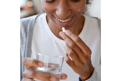 Woman taking a supplement for beauty-from-within or joint health.