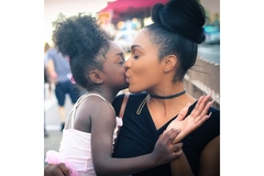 A mother and daughter kissing.