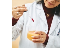 Image A female scientist holding a dropper with red liquid.