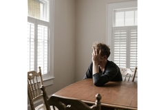 Image Person with a mental health issue, sitting at a table with hands in their hair.