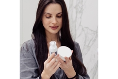 Image A woman looking at two skin care products.