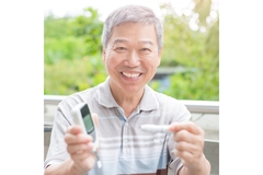 Image Older man with diabetes, smiling, and holding up his insulin measuring machine.