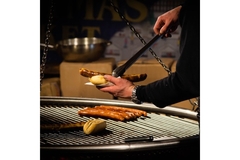 Image plant-based hot dog being taken from the grill and put into a bun.