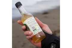 Image person holding a glass bottle in hand showing h eqr code printed on the bottle